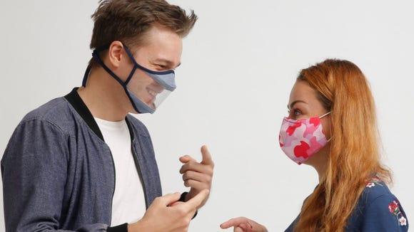 The benefits of clear face masks—and where to buy them by RAFI NOVA A young man wearing a clear transparent mask is smiling and talking to a young woman in a regular mask who is looking at him